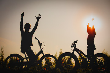 happy boy and girl riding bikes in sunset nature