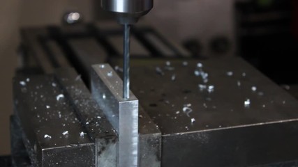 Drill press lowering and peck drilling into piece of aluminum side angle