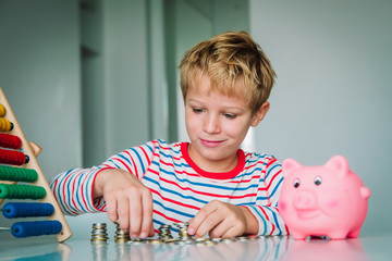 child counting money, boy put coins into piggy bank - 296507826