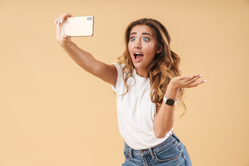Portrait of surprised woman wondering while taking selfie on cellphone
