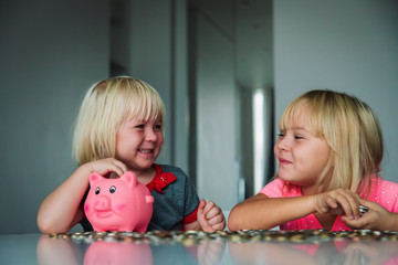 cute girls saving money, kids put coins into piggy bank