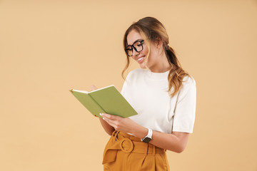 Image of attractive woman smiling and writing down notes in diary book