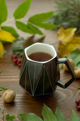 A cozy warm cup of delicious tea on a wooden and foliage background