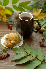  A cozy warm cup of delicious tea with homemade cookies on a wooden and foliage background