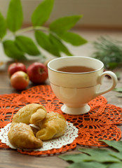  A cozy warm cup of delicious tea with homemade cookies on a wooden and foliage background