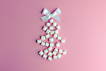 Obraz na płótnie Canvas Creative christmas tree.Creative layout of Christmas tree of white marshmallows and white bow on a pink background. Christmas tree made of sweets. Save space