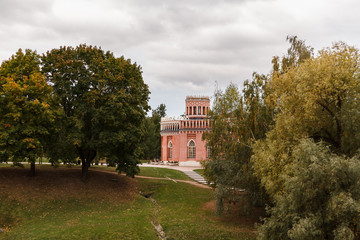 The tower of a beautiful old castle surrounded by autumn trees against a gray sky.