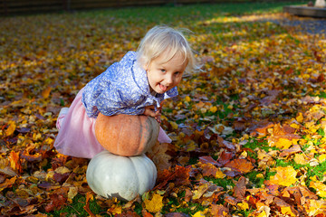 cute blond 3 year old girl with pumpkins