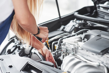 Almost ready. Car addicted woman repairs black car indoors in garage at daytime