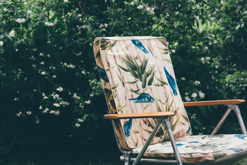 un fauteuil vintage dans un jardin. Un vieille chaise pliante dans un parc. Un fauteuil des années...