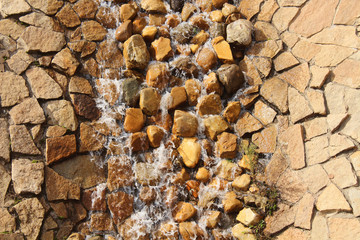 A decorative waterfall flows over stones. Close-up. Background.