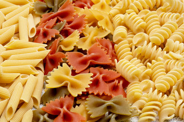 Types of uncooked pasta. Pasta penne, fusilli, color farfalle dry. Flat lay, top view, filled frame