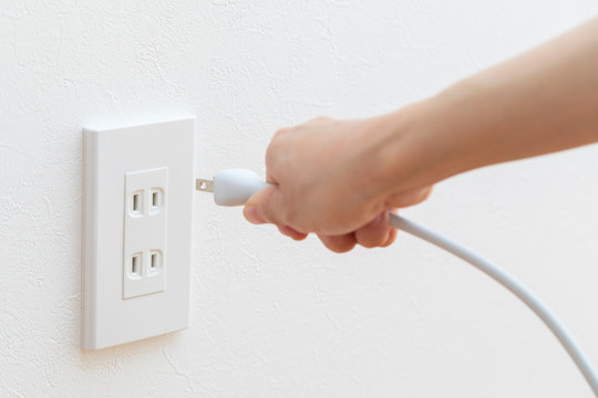 コンセントにコードを差し込みう若い女性の手元
