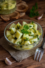 Marinated zucchini with herbs in a transparent cup on a wooden table