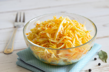 Sauerkraut with carrots in a transparent cup on a white background