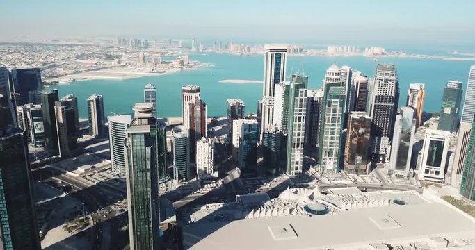 Aerial moving-forward view of futuristic global city in the desert, with high buildings and towers, near the sea, Doha, Qatar