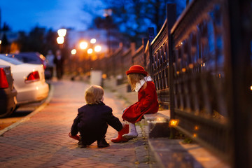 boy helps a girl to shoe boots, evening street