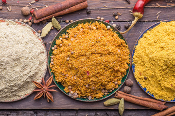 Heaps of various ground spices in little plate on wooden background. Georgian spices, Indian spices, Arabian spices. Spice variety. Herbs and spices