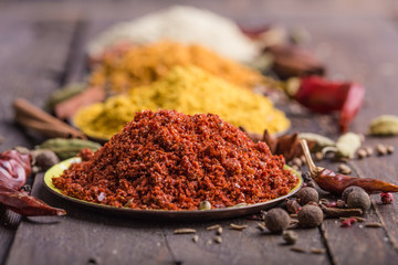 Heaps of various ground spices in little plate on wooden background. Georgian spices, Indian spices, Arabian spices. Spice variety. Herbs and spices