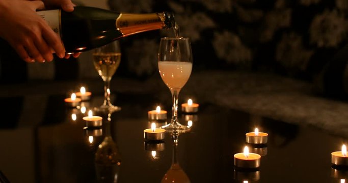 Women pouring sparkling champagne in glasses with romantic candles flames on a table. warm and elegant wedding celebration ambiance, Blurred to focused. Dalian, China - 1 October 2018
