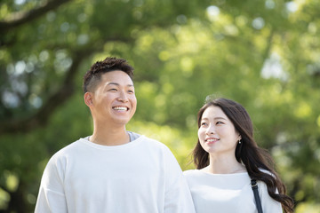 Fototapeta premium 綺麗な緑を背景に仲良く歩く若い男女