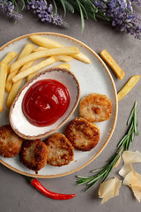 french fries, meat cutlets and ketchup in a white plate