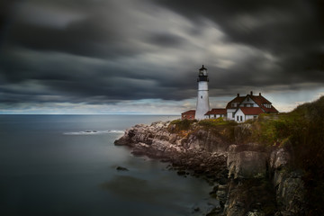 A lighthouse on a cliff on the shore of the Atlantic Ocean against a dramatic sky. Long exposure....