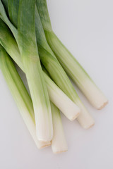 Close up of a bunch of fresh green leeks in a white background