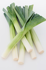 Bunch of fresh full leeks in a white background. Green and white leeks.