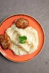 mashed potatoes and meat cutlets in an orange plate
