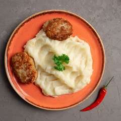 mashed potatoes and meat cutlets in an orange plate