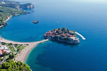 Flight over the island city (Sveti Stefan). landscape below (aerial photo from a paraglider) with the coast and the blue sea, Montenegro