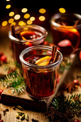 Christmas mulled red wine with spices and citrus fruits on a wooden rustic table, close-up....
