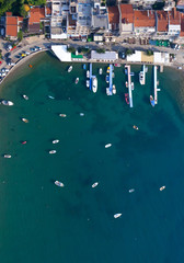 Fototapeta na wymiar Vertically down- boats and yachts at the pier and in the bay. landscape below (aerial photo from a paraglider) with the coast and the blue sea, Montenegro