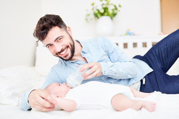 Obraz na płótnie Canvas Happy father gives baby the bottle
