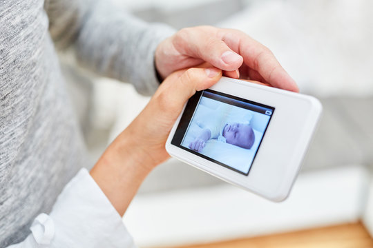 Parents Look At A Baby Monitor With Camera