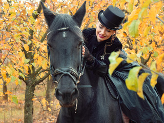 Obraz premium girl in a black dress riding a black horse
