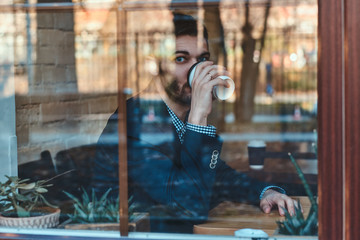 Handsome man is enjoying his coffee while sitting at cafe near window.
