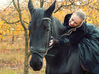 girl in a black dress riding a black horse