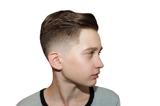 Stylish modern retro haircut side part with mid fade with parting of a schoolboy guy in a barbershop on an isolated white background