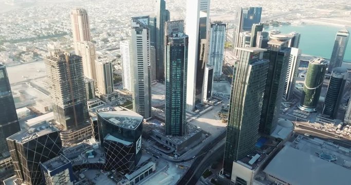 Aerial rising view of a business districts filled with towers and high rise buildings in a futuristic developped city, Doha, capital of Qatar