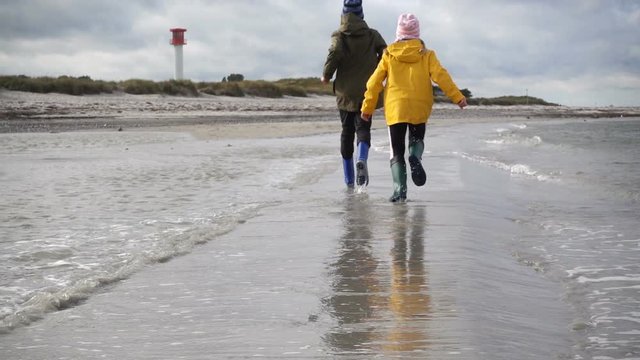 Joyful brother and sister running in water of Baltic sea in northern Germany