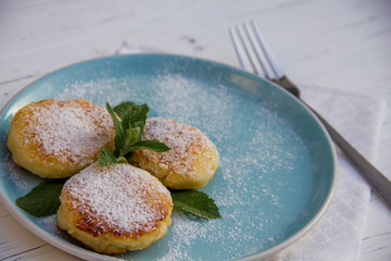 cheesecake on a blue plate with a fork and a cotton cloth on light wooden background