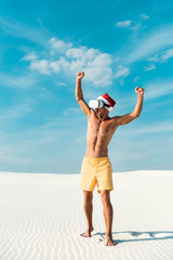 sexy man in santa hat with virtual reality headset showing yes gesture on beach in Maldives
