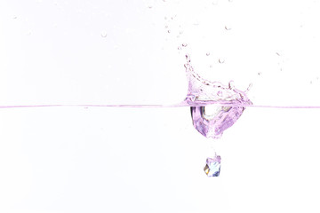 Beautiful and cool splashes of water from falling into it purple transparent crystals