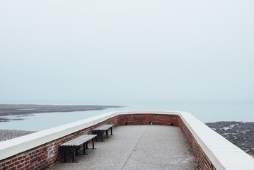 Une jetée sur la mer. Un lieu de repos au bord de la mer. Des bancs face à la mer. L'absence de touristes à la mer.