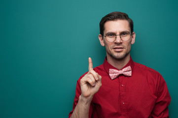 Portrait of a cute young man showing finger on a green background