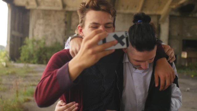 Drunk youth laughing and take a selfie outside. Medium shot.