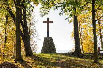 Wooden Christian religious cross on the background of green trees