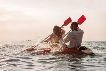 Couple walks by kayak at sunset sea